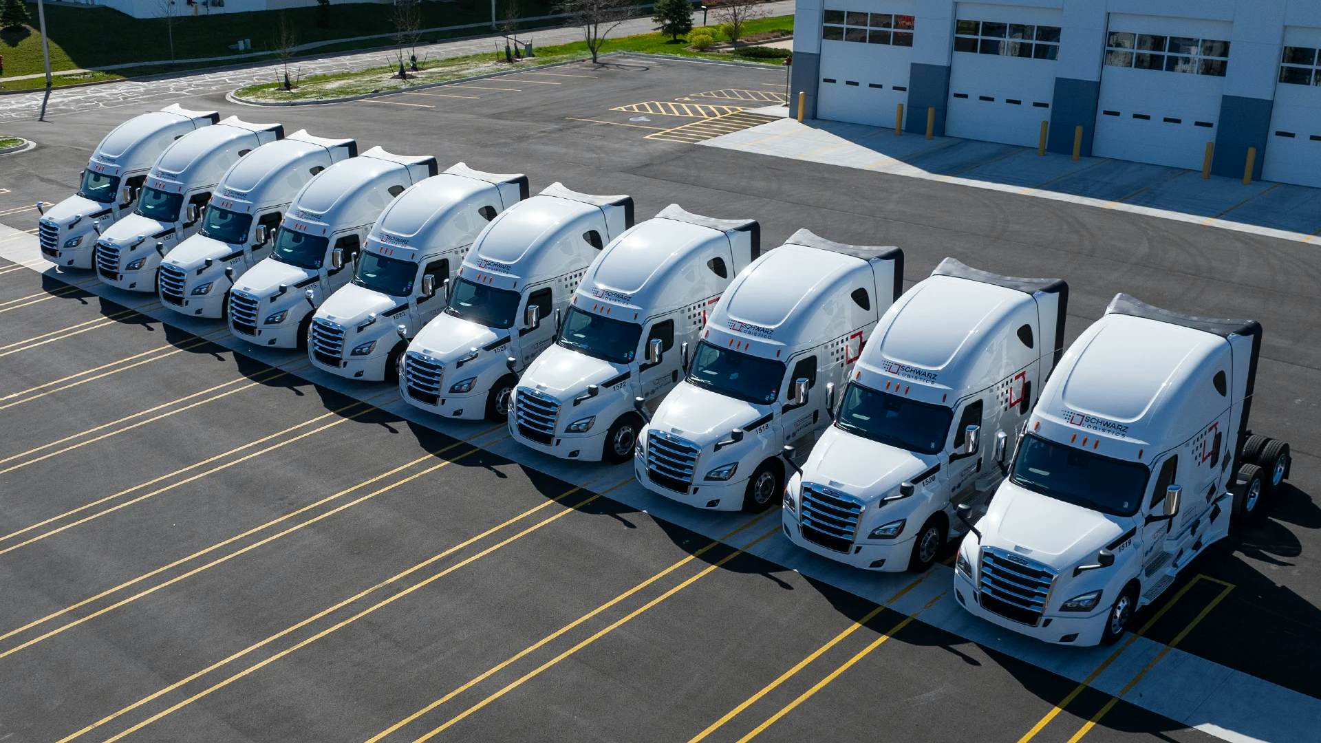 An aerial view of a fleet of commercial trucks neatly parked in a large parking area.