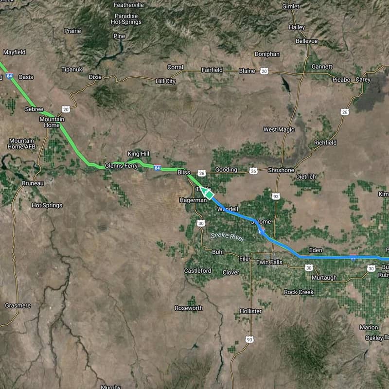 Satellite map image showing a section of the Interstate 84 highway in Idaho, running through towns like Mountain Home, Glenns Ferry, Bliss, and towards Twin Falls. The map shows a detailed aerial view of the terrain with roadways marked by green lines, and the Snake River highlighted in blue, indicating a geographical route for travel or logistics tracking.