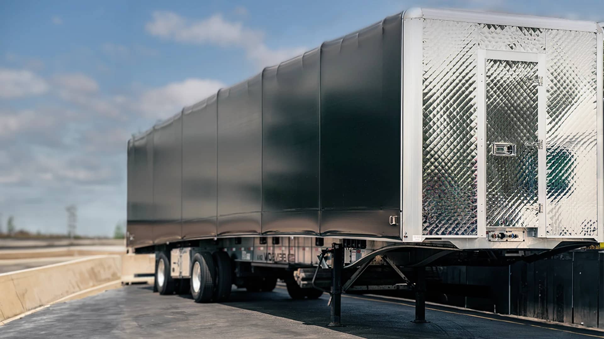 Black conestoga trailer in a parking lot.