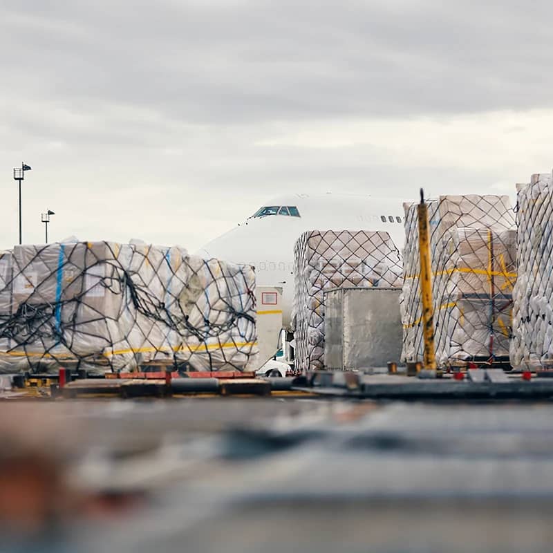 A cargo plane being loaded with containers at an airport freight terminal.