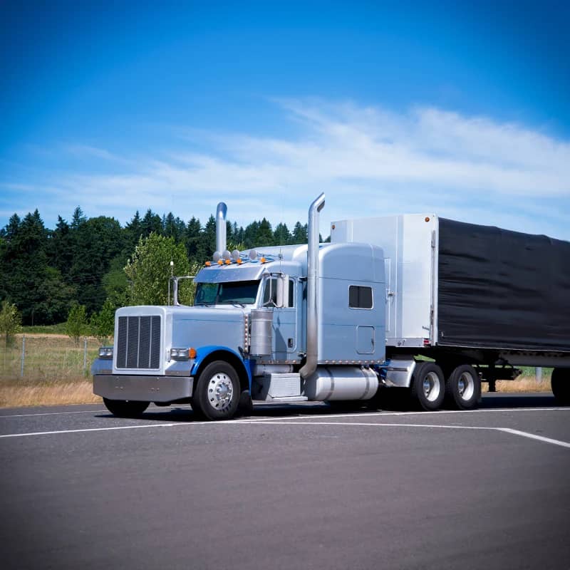 Silver classic semi truck, black Conestoga, clear sky.