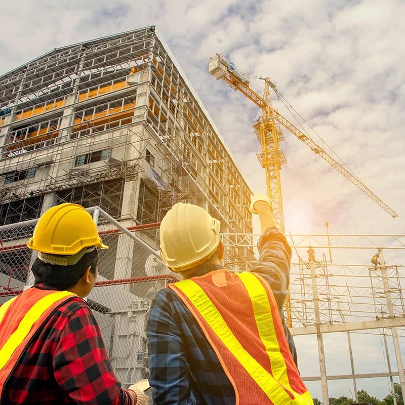 Workers in hardhats at construction site with crane.