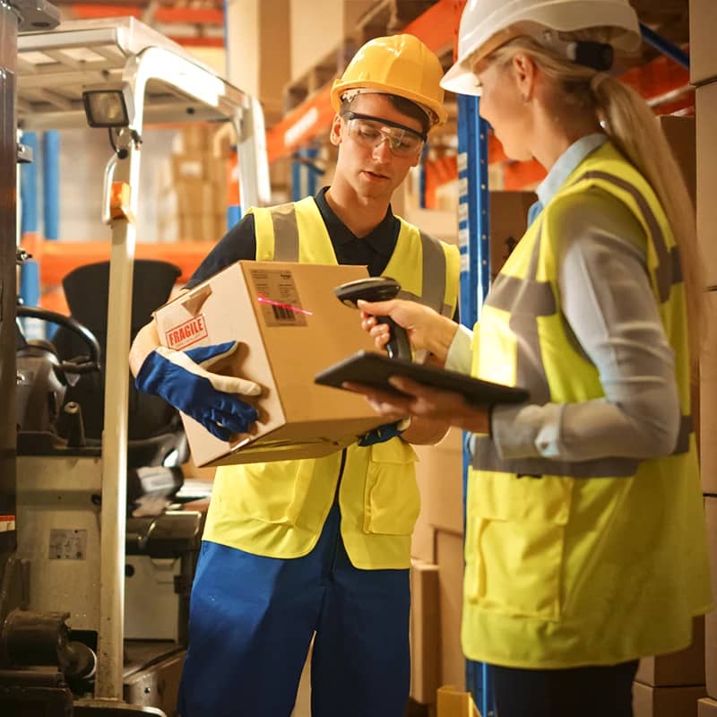 Two warehouse workers with a box and scanner.