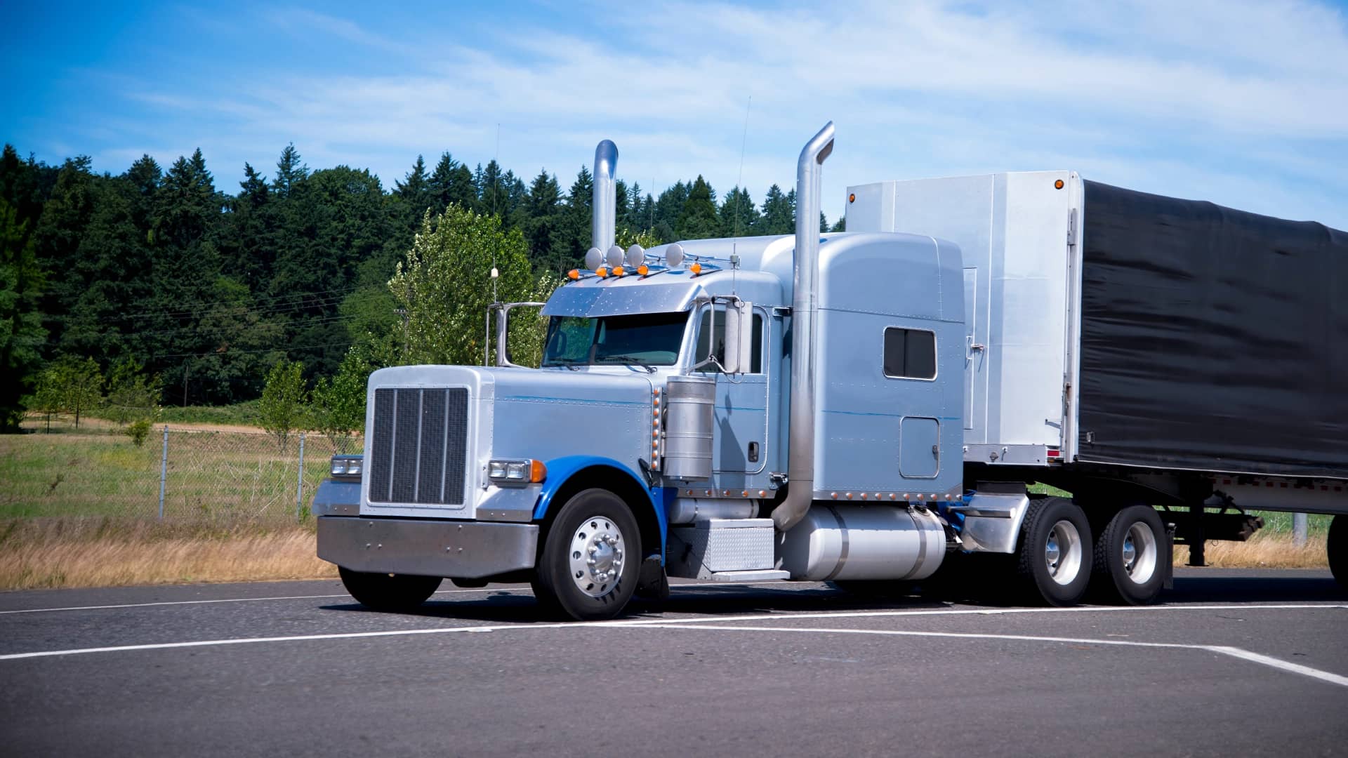 A classic semi truck with conestoga trailer parked at a rest area.