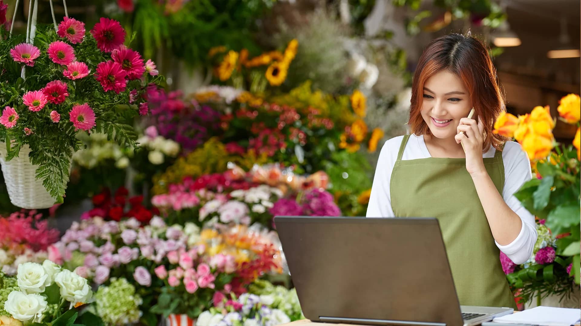 A woman talking on the phone in a flower shop.