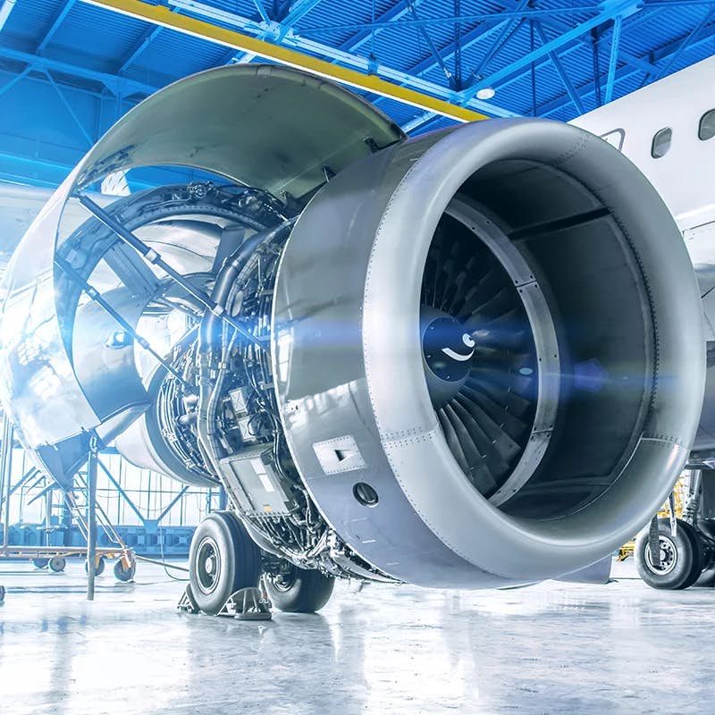 Jet engine maintenance in an aerospace facility with exposed turbine and undercarriage.