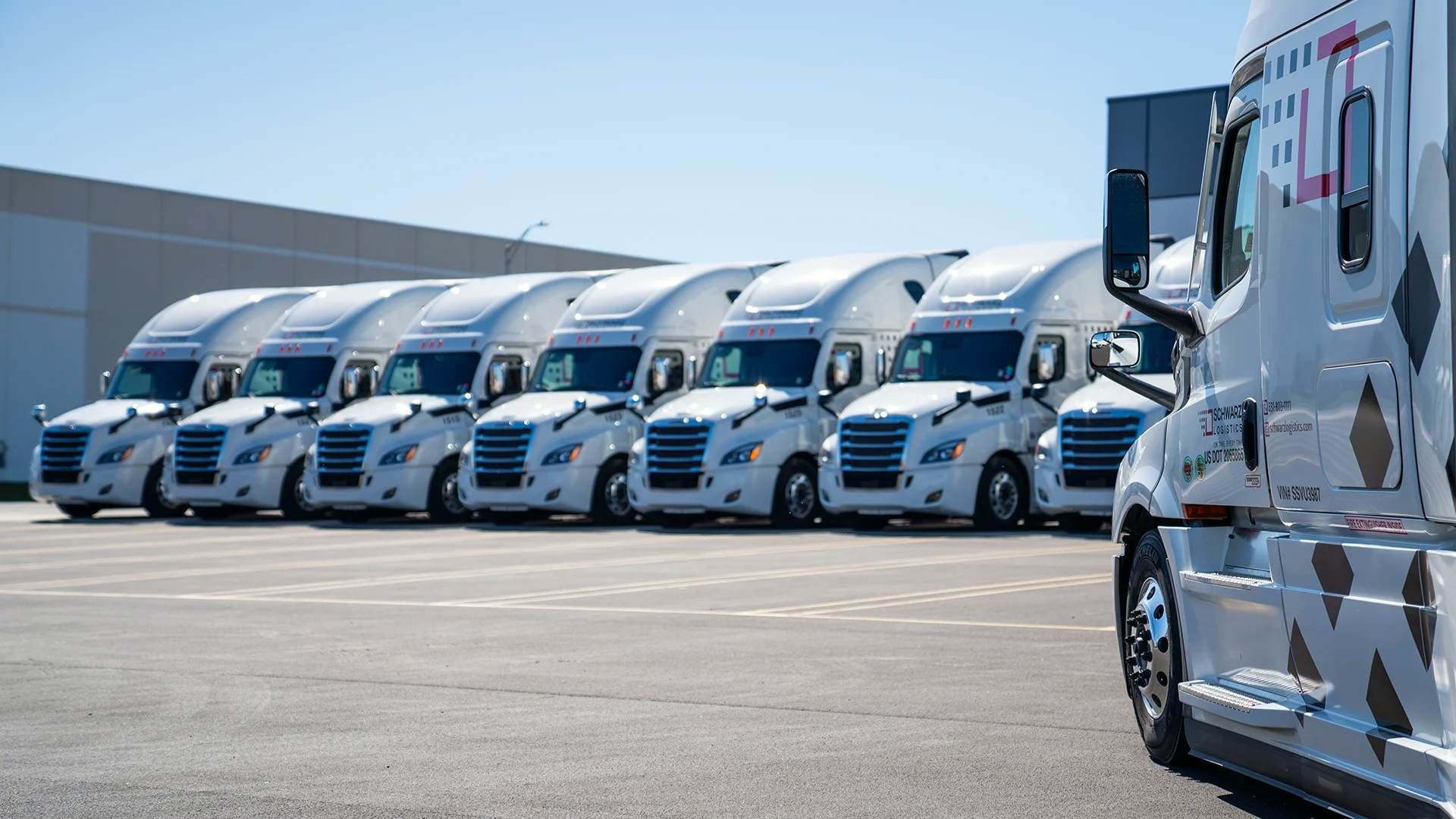 Schwarz Logistics fleet of modern white semi-trucks with aerodynamic cabs lined up neatly in a parking area.
