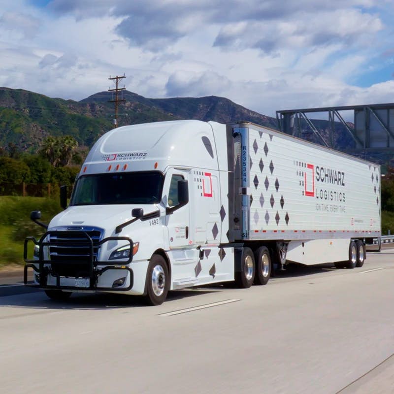 A "Schwarz Logistics" semi-trailer truck in motion on a highway.