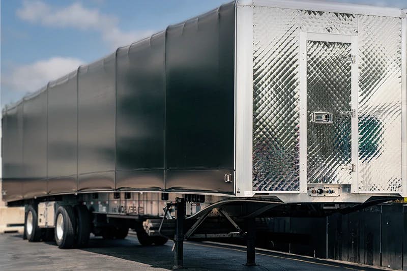 A close-up of a conestoga trailer, characterized by its rolling tarp system that provides cover and protection for the freight.