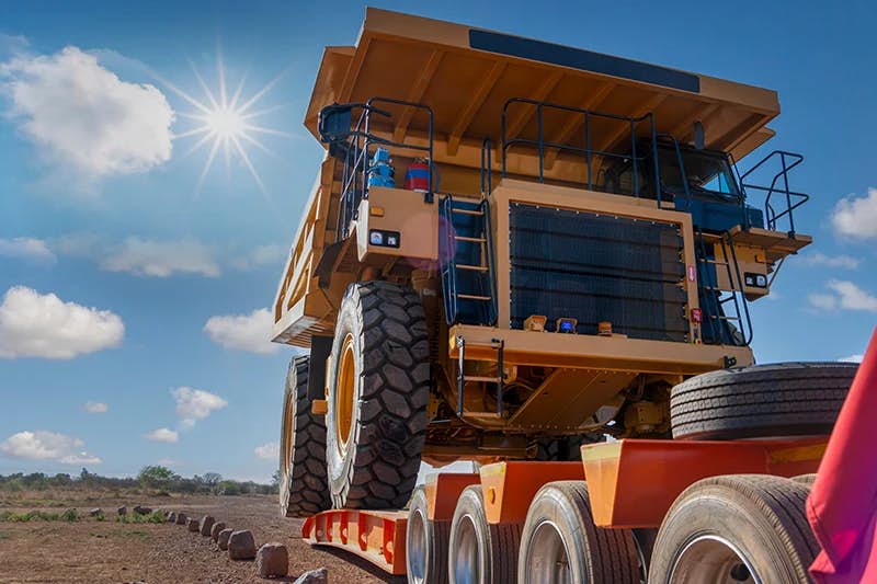A massive mining dump truck, often referred to as a haul truck, being transported on a specialized trailer.