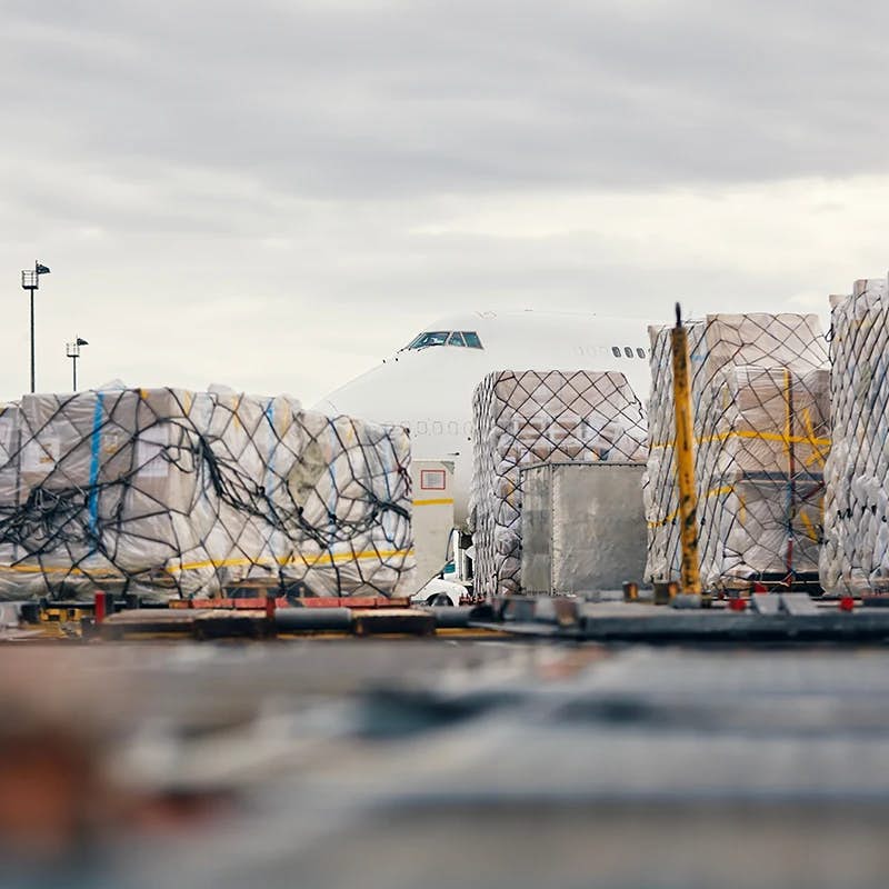 A cargo plane being loaded with containers at an airport freight terminal.