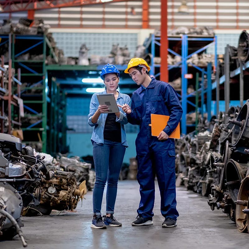 Workers with tablet in automotive parts warehouse.