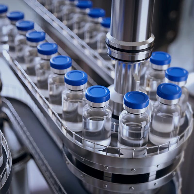 Vials with blue caps on a pharmaceutical production line.