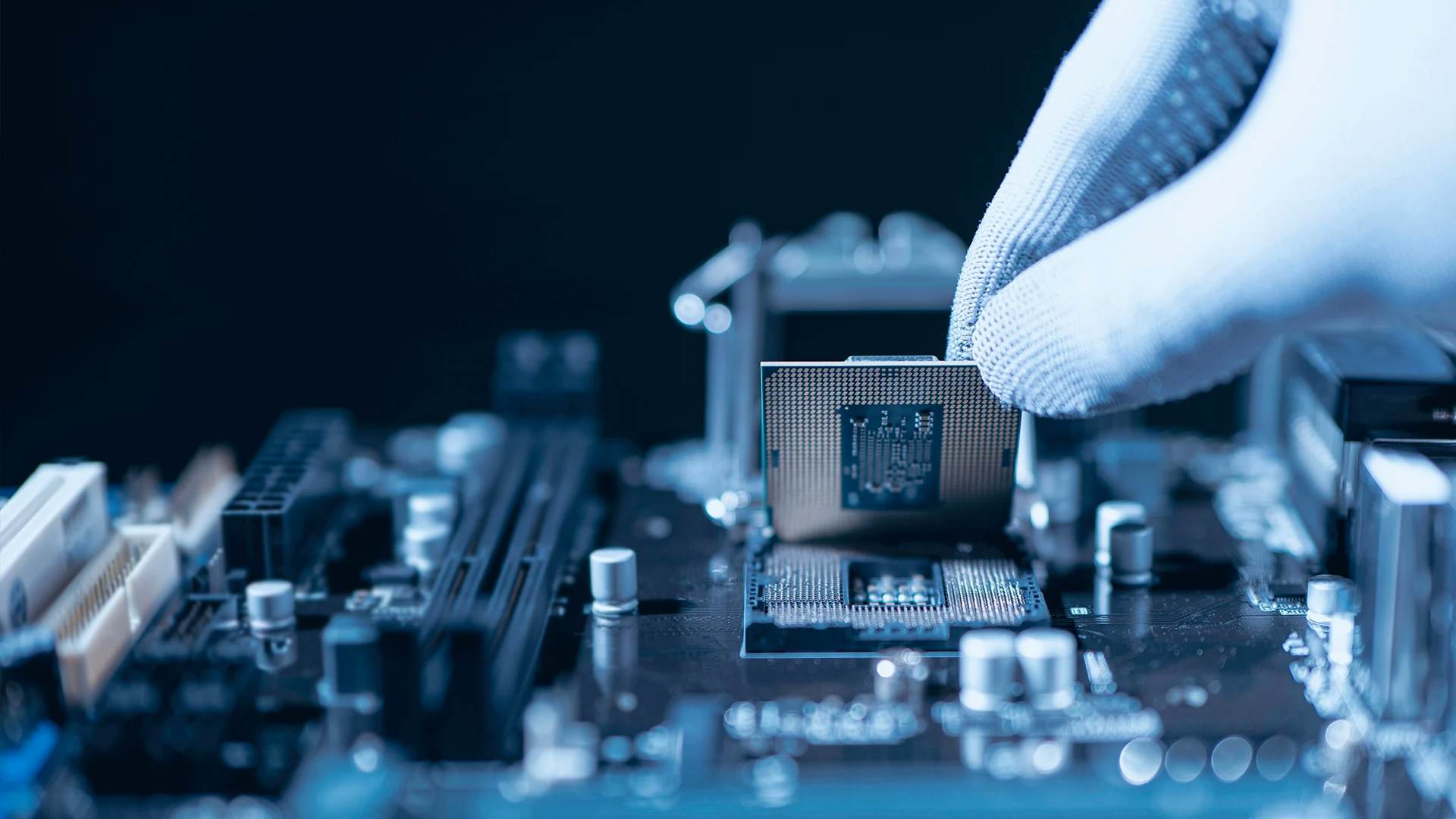 A gloved hand installs a CPU on a motherboard, showcasing technology and precision in electronics assembly.
